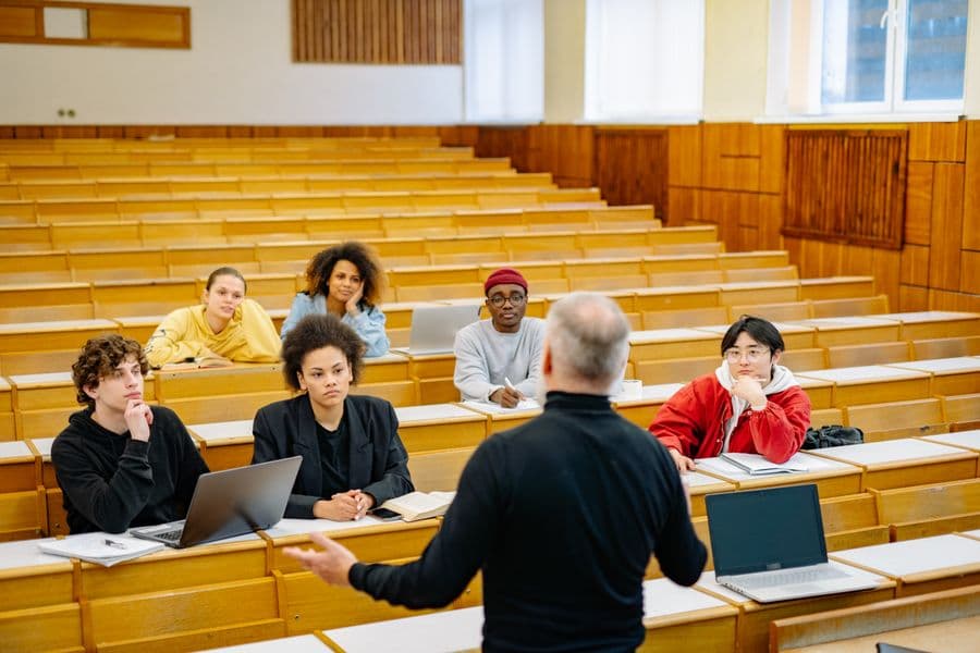 A lecturer addressing a full classroom of students.